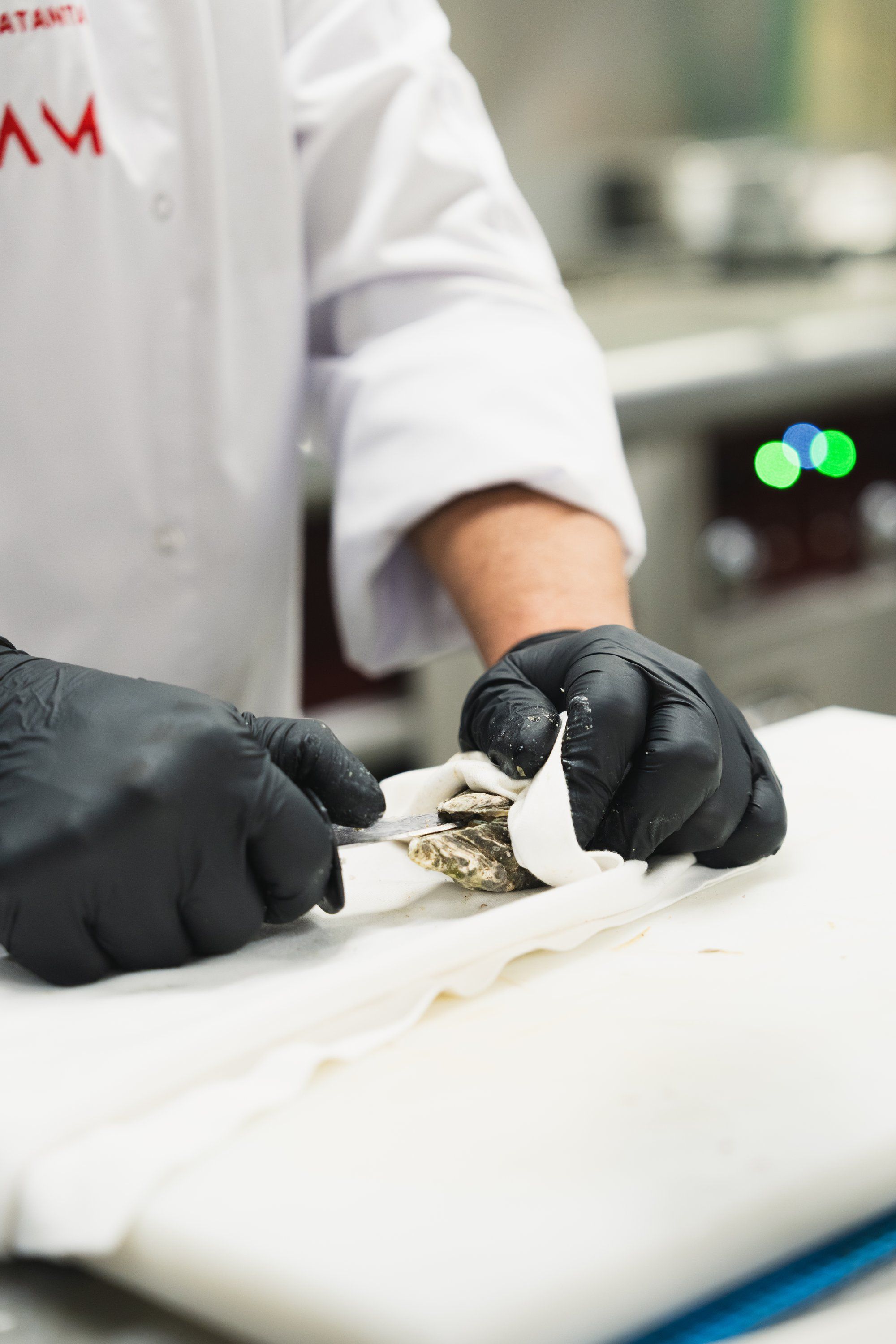 Manos del chef abriendo una ostra